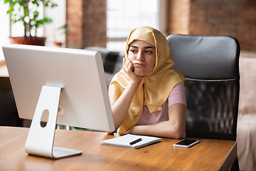 Image showing A pretty young muslim woman at home during quarantine and self-insulation, remote working, shopping, studying, watching cinema