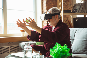 Image showing Mature senior older man during quarantine, realizing how important stay at home during virus outbreak, trying on VR-headset, playing, watching