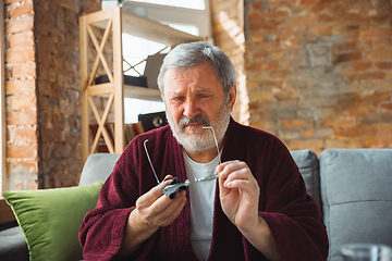 Image showing Mature senior older man during quarantine, realizing how important stay at home during virus outbreak, suffers of glaucoma, eye deseases