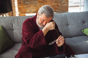 Image showing Mature senior older man during quarantine, realizing how important stay at home during virus outbreak, suffers of glaucoma, eye deseases