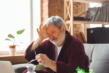 Image showing Mature senior older man during quarantine, realizing how important stay at home during virus outbreak, suffers of glaucoma, eye deseases