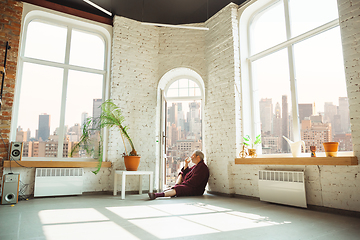 Image showing Mature senior older man during quarantine, realizing how important stay at home during virus outbreak, looking throught window on day New York city