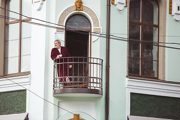 Image showing Mature senior older man during quarantine, realizing how important stay at home during virus outbreak, drinking coffee on the balcony