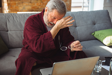 Image showing Mature senior older man during quarantine, realizing how important stay at home during virus outbreak, suffers of glaucoma, eye deseases