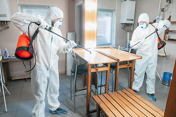 Image showing Coronavirus Pandemic. A disinfector in a protective suit and mask sprays disinfectants in the house or office