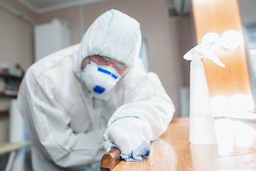 Image showing Coronavirus Pandemic. A disinfector in a protective suit and mask sprays disinfectants in the house or office