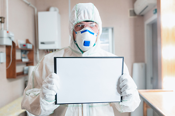 Image showing Coronavirus Pandemic. A disinfector in a protective suit and mask sprays disinfectants in the house or office