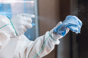 Image showing Coronavirus Pandemic. A disinfector in a protective suit and mask sprays disinfectants in the house or office