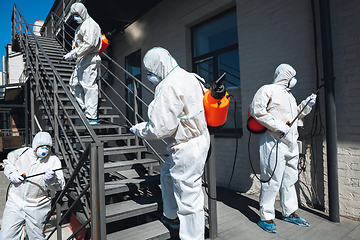 Image showing Coronavirus Pandemic. A disinfectors in a protective suit and mask spray disinfectants in the house or office