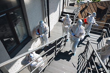 Image showing Coronavirus Pandemic. A disinfectors in a protective suit and mask spray disinfectants in the house or office