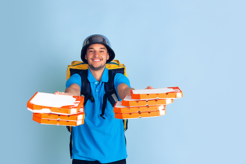 Image showing Contacless delivery service during quarantine. Man delivers food and shopping bags during insulation. Emotions of deliveryman isolated on blue background.