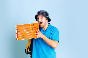 Image showing Contacless delivery service during quarantine. Man delivers food and shopping bags during insulation. Emotions of deliveryman isolated on blue background.