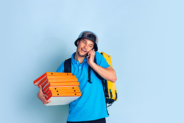 Image showing Contacless delivery service during quarantine. Man delivers food and shopping bags during insulation. Emotions of deliveryman isolated on blue background.