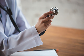 Image showing Close up of doctors hands with stethoscope, sheets and pills on wooden background