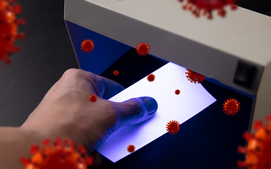 Image showing Male hands checking of banknotes in the detector, 3D models of coronavirus spreding around