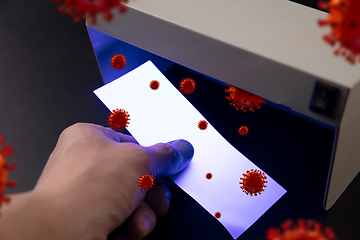 Image showing Male hands checking of banknotes in the detector, 3D models of coronavirus spreding around