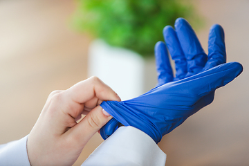 Image showing Close up of doctors hands wearing blue protective gloves on wooden table background