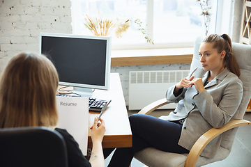 Image showing Young woman in suit sitting in office during the job interview with female employee, boss or HR-manager, talking, thinking, looks confident