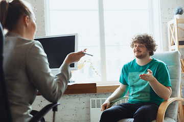 Image showing Young man sitting in office during the job interview with female employee, boss or HR-manager, talking, thinking, looks confident