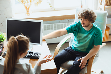 Image showing Young man sitting in office during the job interview with female employee, boss or HR-manager, talking, thinking, looks confident