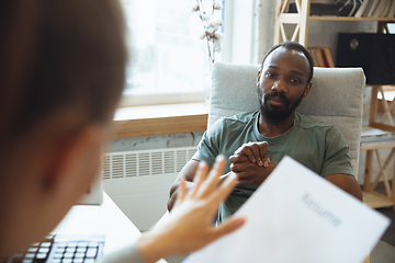 Image showing Young man sitting in office during the job interview with female employee, boss or HR-manager, talking, thinking, looks confident