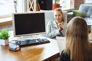 Image showing Young woman in suit sitting in office during the job interview with female employee, boss or HR-manager, talking, thinking, looks confident