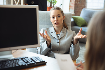 Image showing Young woman in suit sitting in office during the job interview with female employee, boss or HR-manager, talking, thinking, looks confident