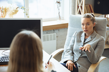 Image showing Young woman in suit sitting in office during the job interview with female employee, boss or HR-manager, talking, thinking, looks confident