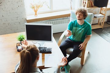 Image showing Young man sitting in office during the job interview with female employee, boss or HR-manager, talking, thinking, looks confident