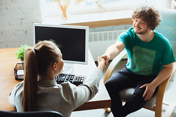 Image showing Young man sitting in office during the job interview with female employee, boss or HR-manager, talking, thinking, looks confident