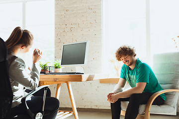 Image showing Young man sitting in office during the job interview with female employee, boss or HR-manager, talking, thinking, looks confident