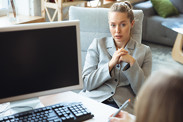 Image showing Young woman in suit sitting in office during the job interview with female employee, boss or HR-manager, talking, thinking, looks confident