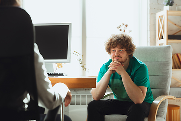 Image showing Young man sitting in office during the job interview with female employee, boss or HR-manager, talking, thinking, looks confident