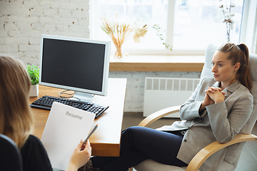 Image showing Young woman in suit sitting in office during the job interview with female employee, boss or HR-manager, talking, thinking, looks confident