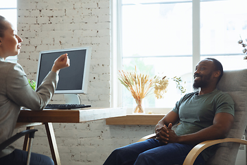 Image showing Young man sitting in office during the job interview with female employee, boss or HR-manager, talking, thinking, looks confident