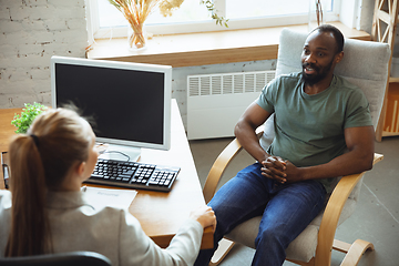 Image showing Young man sitting in office during the job interview with female employee, boss or HR-manager, talking, thinking, looks confident