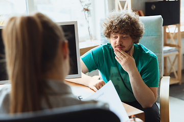 Image showing Young man sitting in office during the job interview with female employee, boss or HR-manager, talking, thinking, looks confident