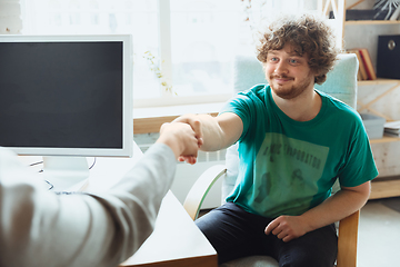 Image showing Young man sitting in office during the job interview with female employee, boss or HR-manager, talking, thinking, looks confident