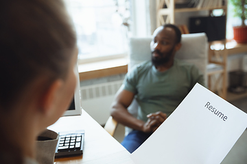 Image showing Young man sitting in office during the job interview with female employee, boss or HR-manager, talking, thinking, looks confident