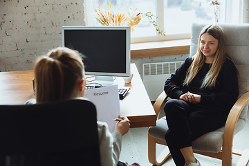 Image showing Young woman sitting in office during the job interview with female employee, boss or HR-manager, talking, thinking, looks confident