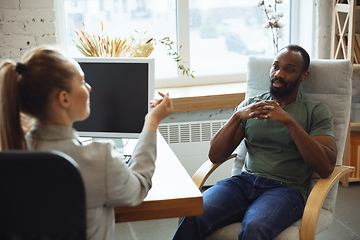 Image showing Young man sitting in office during the job interview with female employee, boss or HR-manager, talking, thinking, looks confident