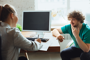 Image showing Young man sitting in office during the job interview with female employee, boss or HR-manager, talking, thinking, looks confident