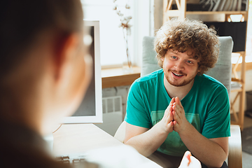 Image showing Young man sitting in office during the job interview with female employee, boss or HR-manager, talking, thinking, looks confident