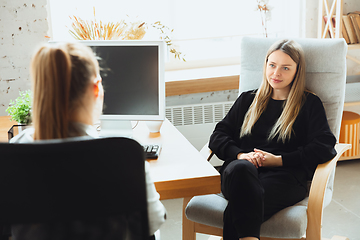 Image showing Young woman sitting in office during the job interview with female employee, boss or HR-manager, talking, thinking, looks confident