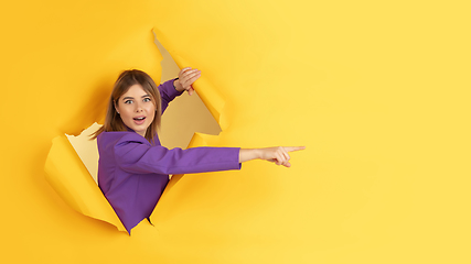 Image showing Cheerful young woman poses in torn yellow paper hole background, emotional and expressive, flyer with copyspace