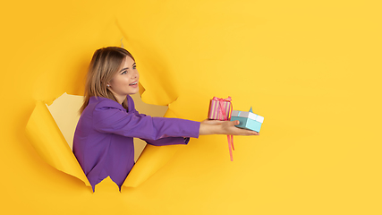 Image showing Cheerful young woman poses in torn yellow paper hole background, emotional and expressive, flyer with copyspace