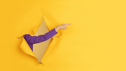 Image showing Female hand gesturing in torn yellow paper hole background, flyer with copyspace