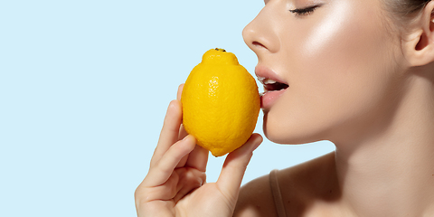 Image showing Close up of beautiful young woman with fresh lemon over white background. Cosmetics and makeup, natural and eco treatment, skin care. Flyer with copyspace.
