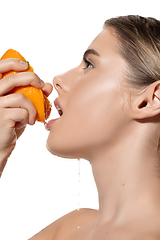 Image showing Vitamins. Close up of beautiful young woman with fresh orange juice pouring over white background. Cosmetics and makeup, natural and eco treatment, skin care