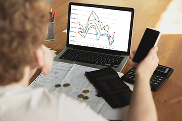 Image showing Close up caucasian upset and despair man doing financial and economical reports with income graphs going down during coronavirus quarantine, problems, empty wallet